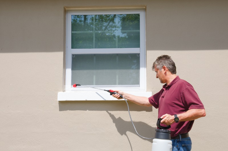 A professional is treating the exteriors of a house with pest control spray in Orlando, FL